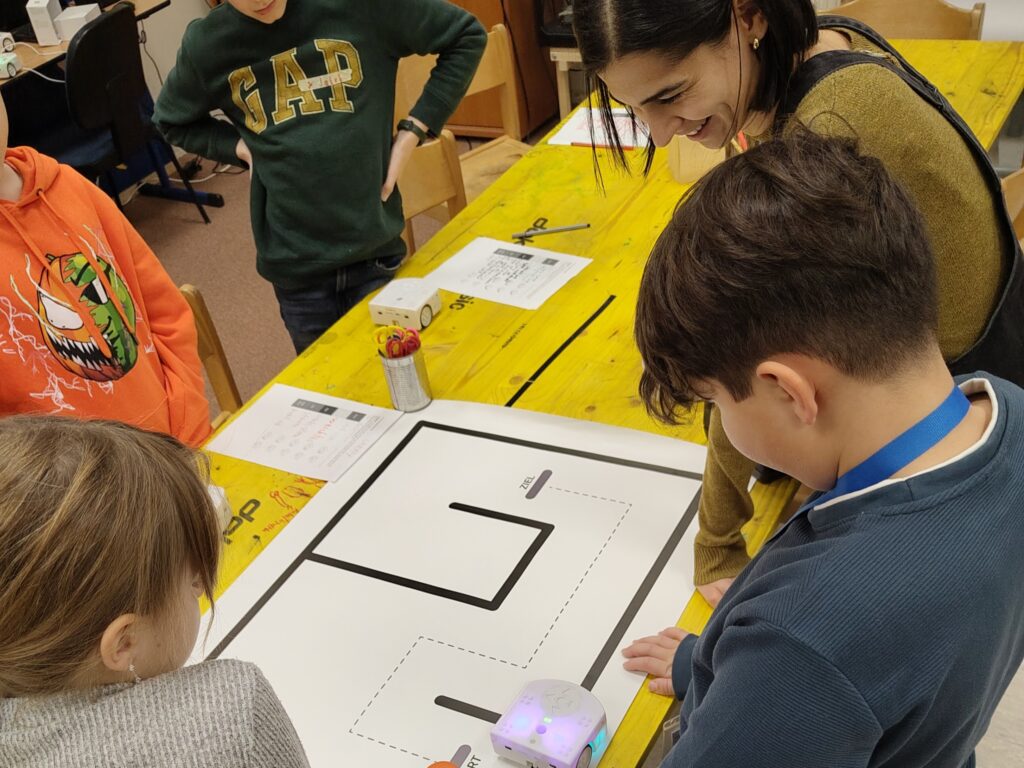 Kinder und TU Studierende, die einen Roboter einer Linie folgen lassen