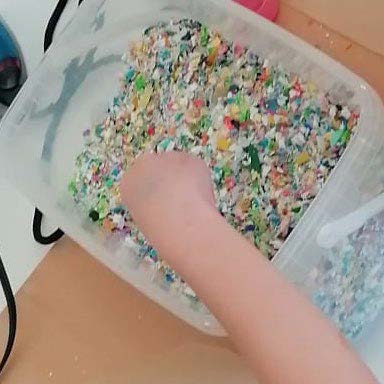 Kind greift in geshredderten Kunststoff um ein DIY zu starten