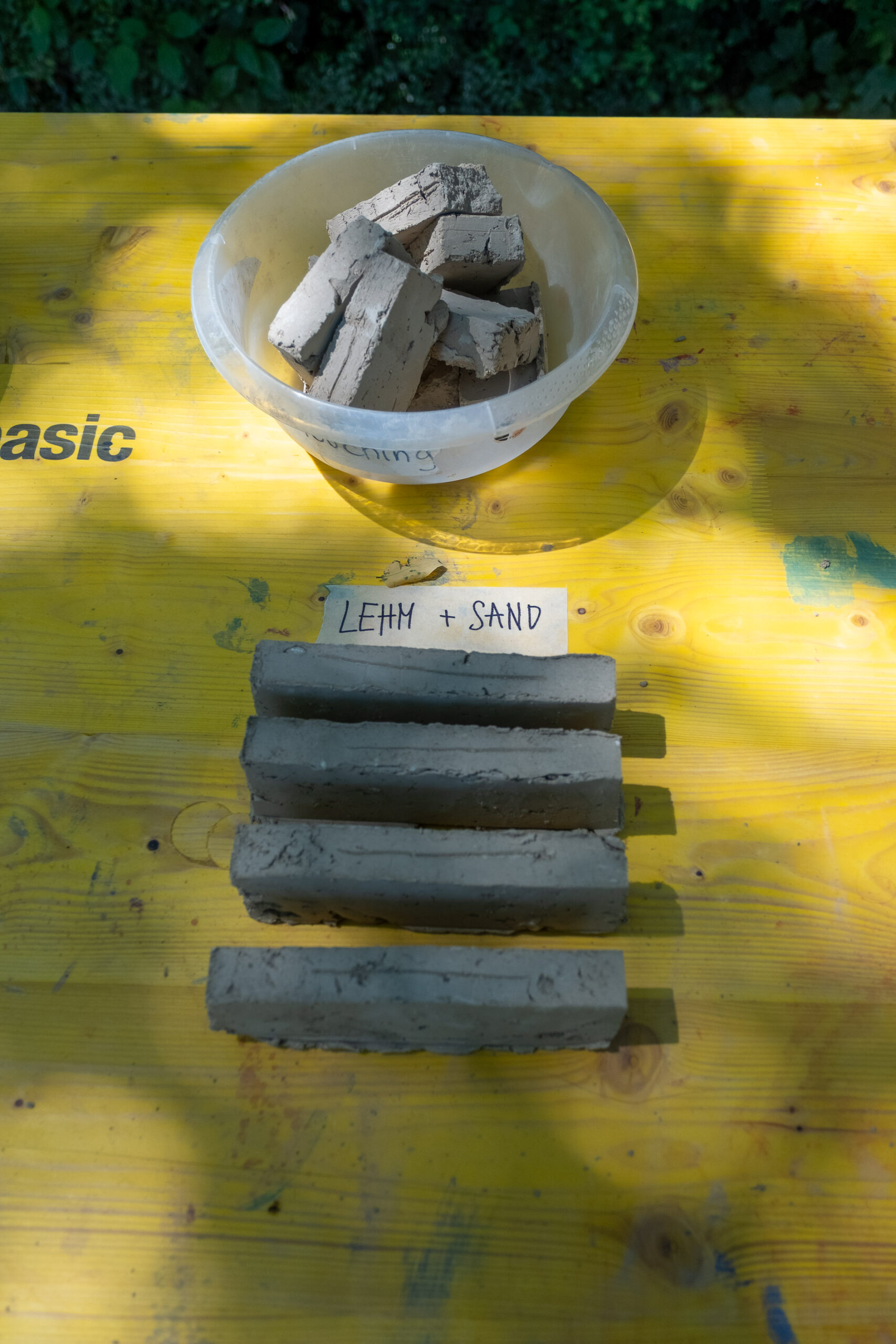 Selbst gepresste Lehmziegel mit der Beschriftung Lehm plus Sand