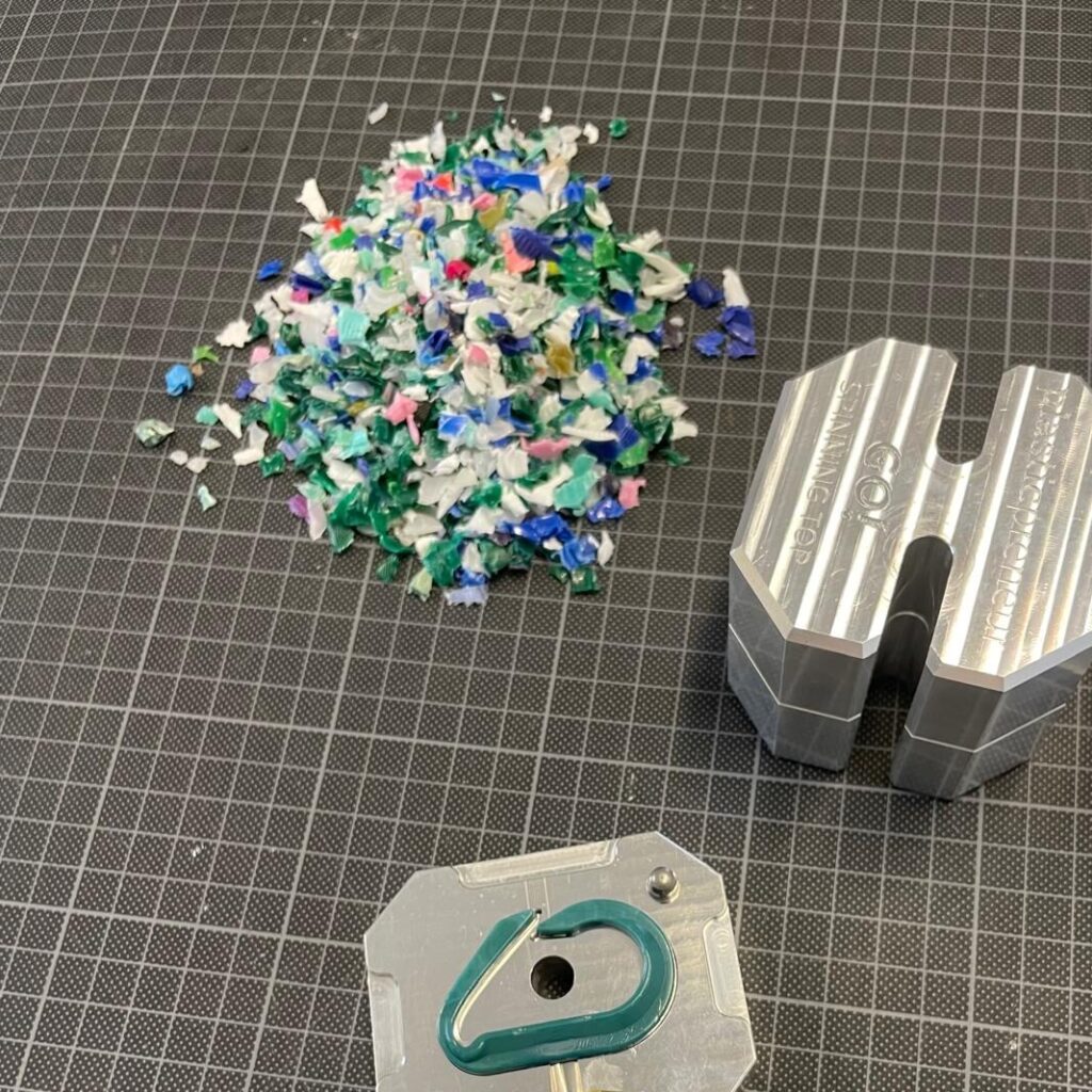 Karabiner in Gussform und geshreddertes Plastik